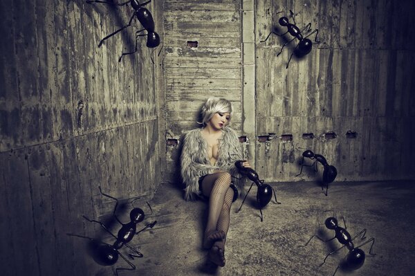 Mädchen, das mit riesigen Ameisen auf dem Sand in einer Scheune sitzt