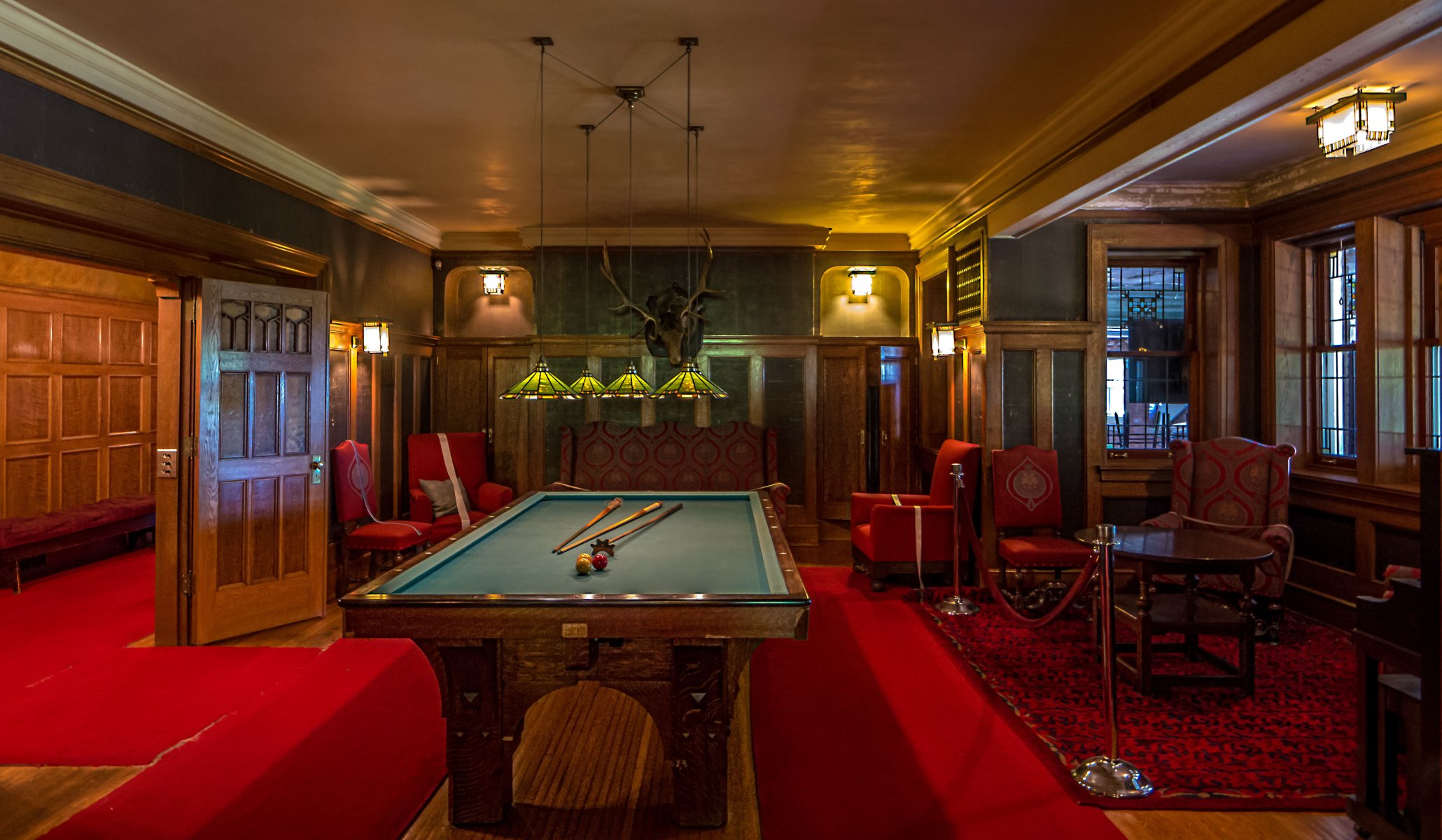 billard kronleuchter roter teppich elchkopf sessel tisch fenster licht