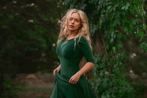 Mädchen im grünen Kleid auf Laubhintergrund