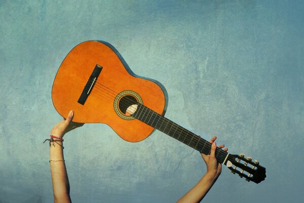 Die Gitarre wird auf blauem Hintergrund gehalten